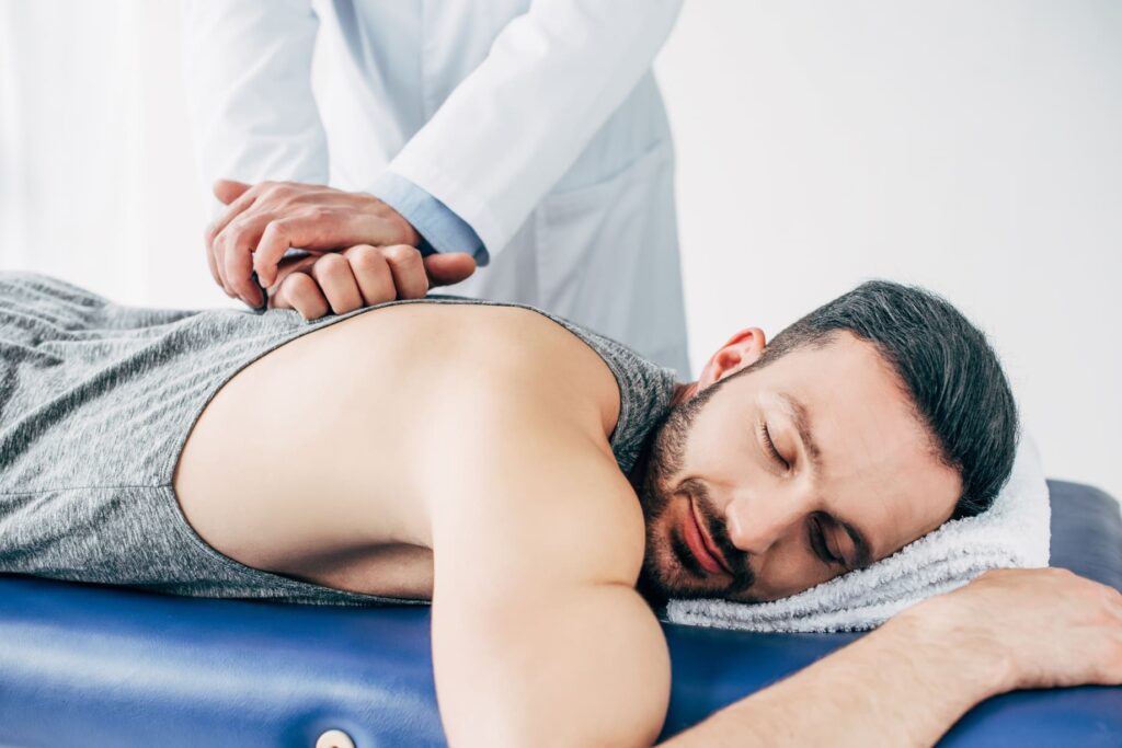 Coburn Chiropractic - chiropractor massaging back of man lying on massag Y9EY5F2