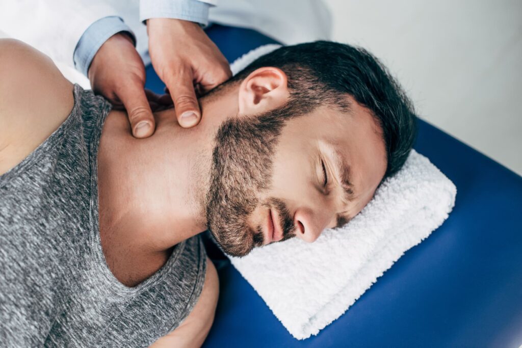 Coburn Chiropractic - chiropractor massaging neck of handsome man lying TEDJJQ8
