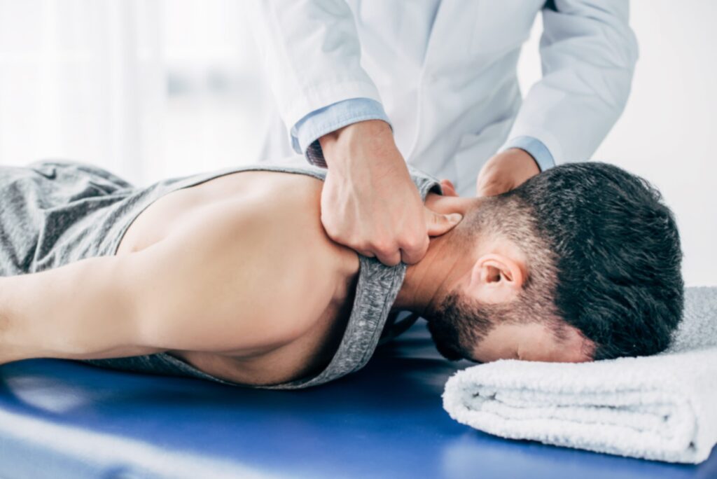 Coburn Chiropractic - chiropractor massaging neck of man lying on massag DAUBLMB scaled 1